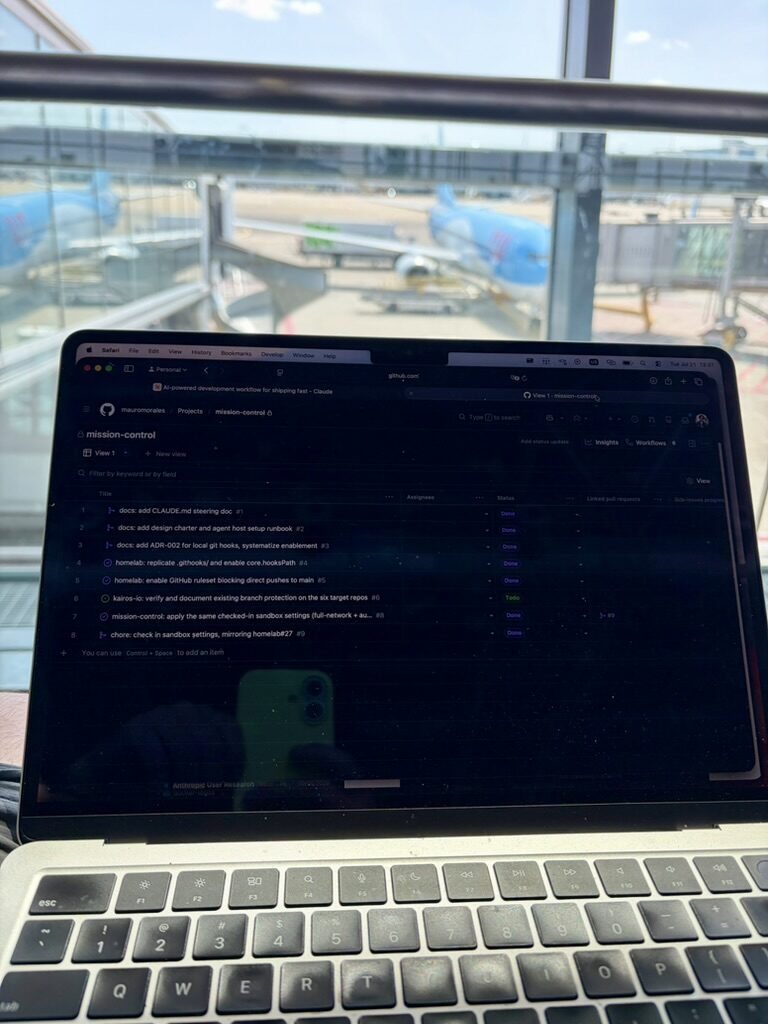The project board open on a laptop at an airport gate